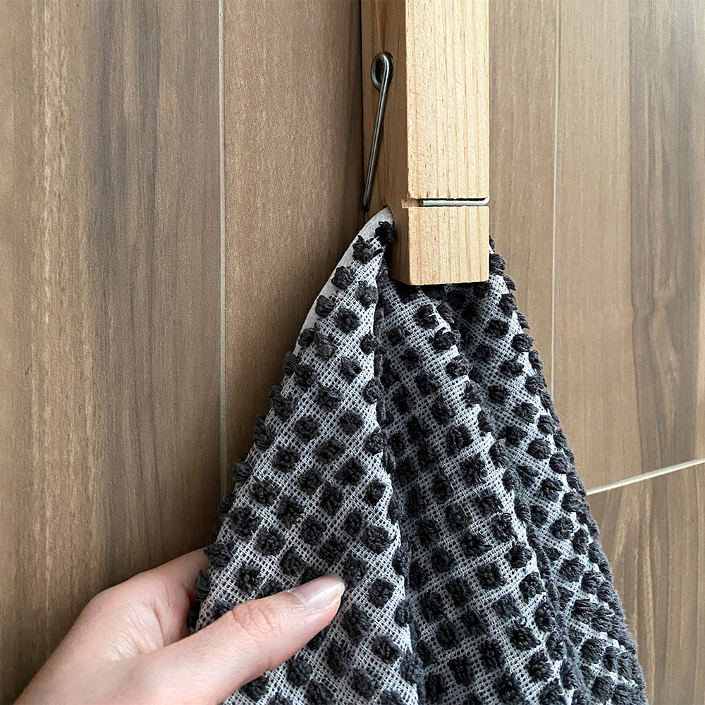 Wall Spring Clip or Peg - shown holding a hand towel in bathroom close up side view