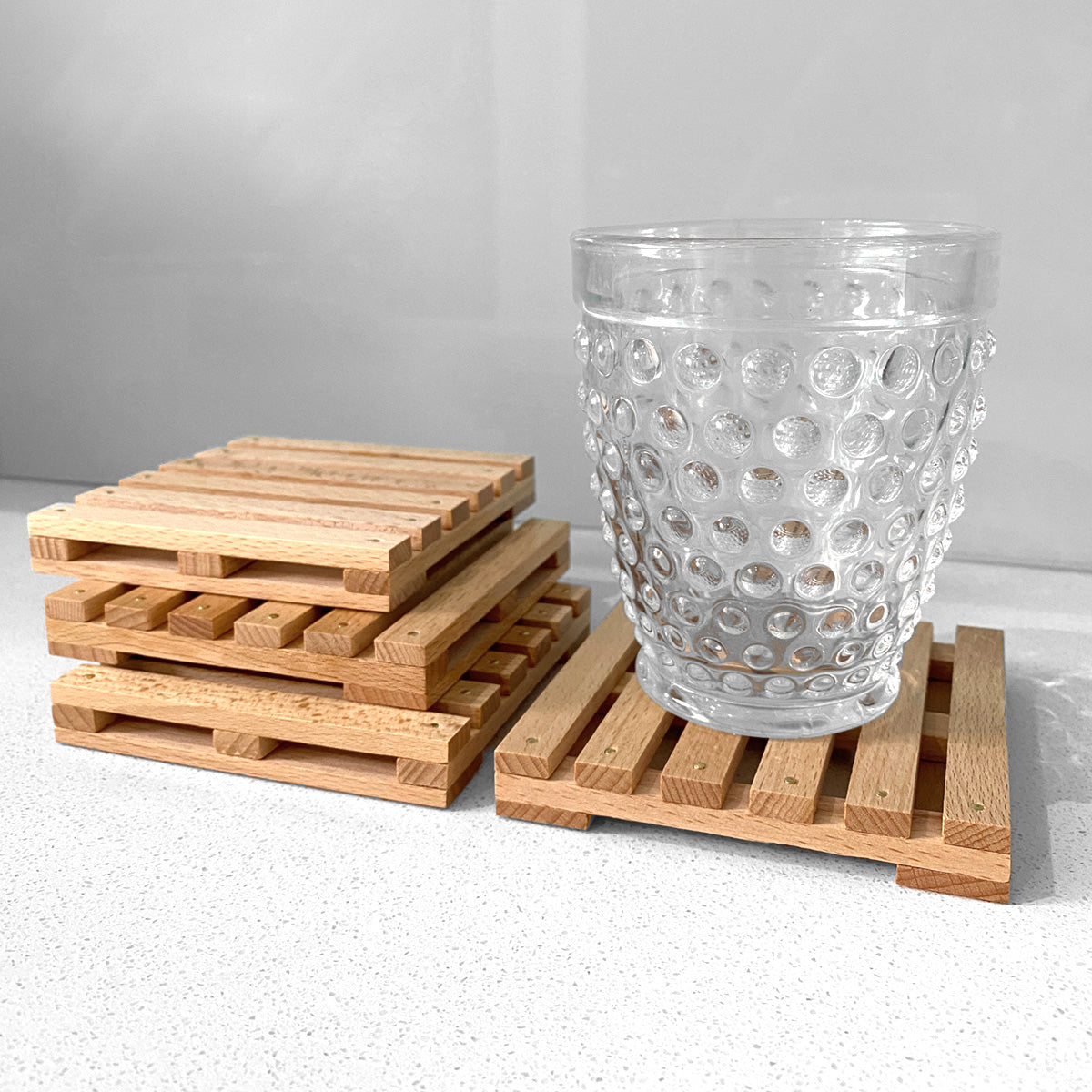 Mini Pallet Wooden Coasters. Shown in situation with a drinking glass and jewellery on top for scale.