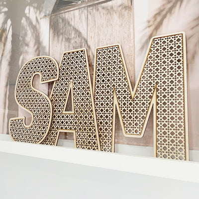 Rattan Letters on Wall Shelf on Boho Styled Backdrop. Spelling the name SAM in rattan wooden letters.
