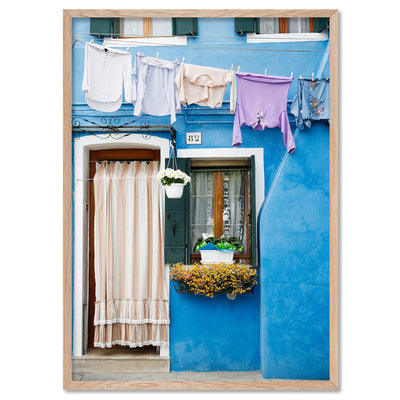 Bright Blue Terrace Washing Burano - Art Print by Victoria's Stories, Poster, Stretched Canvas, or Framed Wall Art Print, shown in a natural timber frame