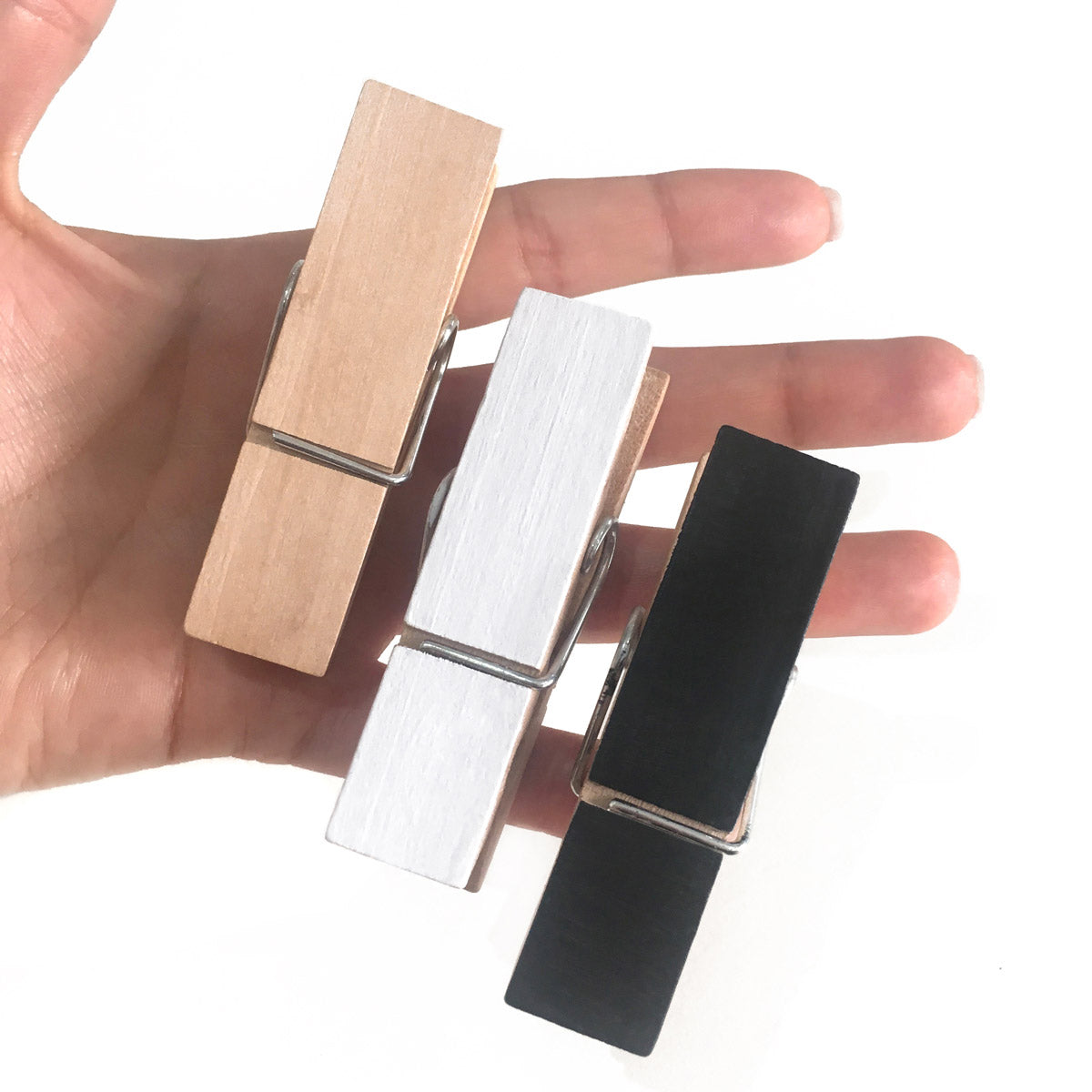 Pair of wood wall clips pegs, held in a hand 